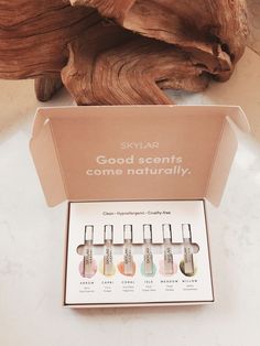 six bottles of skin care products in a cardboard box on a white countertop next to a piece of wood