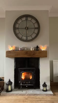 a fireplace with a clock on the wall above it and candles in front of it