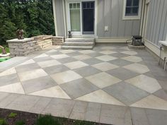 an outdoor patio with stone steps and checkerboard pattern on the concrete, next to a house