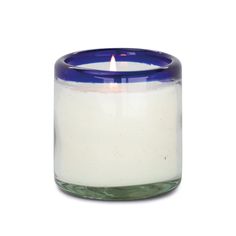 a blue and white candle is sitting in a glass jar on a white surface,