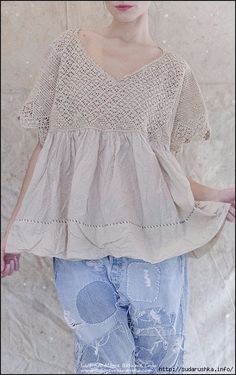 a woman standing in front of a wall wearing ripped jeans and a crochet top