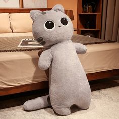 a large gray stuffed animal sitting on top of a bed