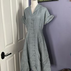 This Grey-Blue Polka Dotted Shirt Dress, With Cuff Sleeves Coming To A Point And Functional Buttons Throughout Skirt And Bodice Is A Perfect Spring Or Summer Piece! It Has A Silky Feel, But Unsure Of Material As The Care Tags/Label Are Not In Garment. One Shoulder Pad Is Missing Easily Replaced One Button Is Securely Attached With A Safety Pin On Inside, And Still Functions This Way. Armpits Have Fading, As Seen In Photos. Dress In First Few Photos Is Shown With Crinoline, Which It Does Not Come Retro Vintage Midi Dress For Daywear, 1950s Collared Daywear Dresses, Classic Vintage Short Sleeve Dress For Daywear, Classic Short Sleeve Vintage Dress For Daywear, 1950s Vintage Dress With Buttons For Daywear, 1950s Collared Day Dresses, 1950s Style Short Sleeve Dresses For Daywear, 1950s Short Sleeve Vintage Dress For Garden Party, 1950s Style Short Sleeve Day Dresses