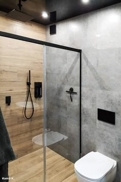 a bathroom with a glass shower door and wooden flooring, along with a white toilet