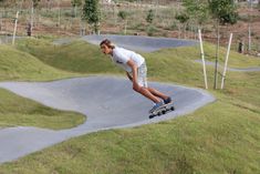 a man riding a skateboard down the side of a ramp in a park on top of green grass