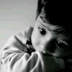 black and white photograph of a young boy with his hands on his face looking at the camera