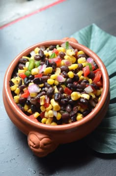 a bowl filled with black beans and corn on top of a green leafy plant