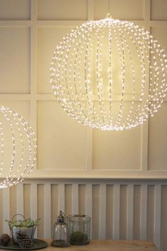 two lights hanging from the ceiling in a room with white walls and wood flooring