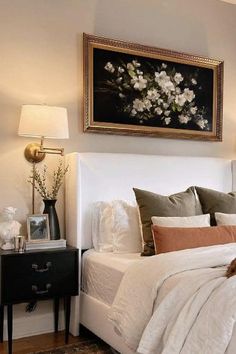 a bedroom with a large painting above the bed