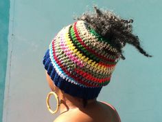 a woman with black hair wearing a multicolored knitted hat and hoop earrings