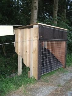 a dog house built into the side of a dirt road in front of trees and grass