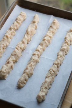 four uncooked dough sticks on a baking sheet