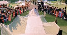 a large group of people standing on top of a grass covered field next to each other