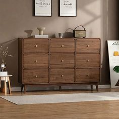 a wooden dresser sitting in a living room next to a wall with pictures on it