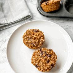 two oatmeal muffins on a plate next to a muffin tin