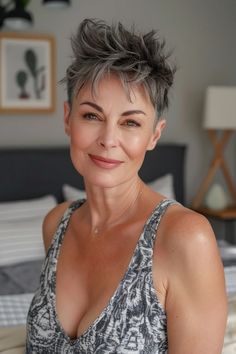 Smiling woman with short gray hair wearing a patterned dress in a cozy, modern bedroom.