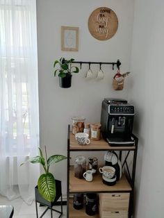 there is a coffee maker and some cups on the shelf in this room with two potted plants