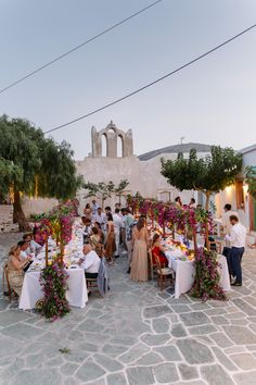 a group of people sitting at tables in front of a building with flowers on it