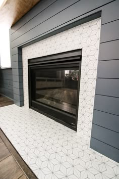 a fireplace with white tiles on it and a black fire place in front of it