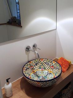 a bowl shaped sink sitting on top of a wooden counter next to a bathroom mirror