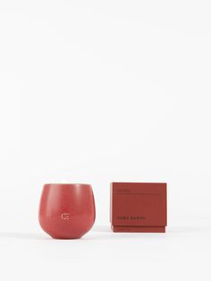 a red cup sitting next to a box on top of a white surface with a card in front of it