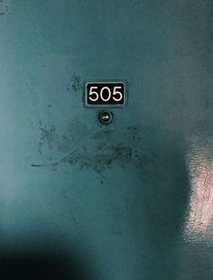 the door is blue and has an old fashioned number plate that reads 505 on it