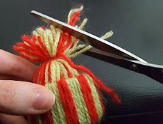 someone is using scissors to cut the yarn into small pieces with red and green stripes