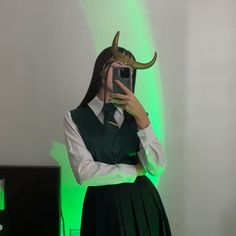 a woman taking a selfie in front of a mirror with horns on her head