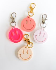 four key chains with smiley faces on them, one is pink and the other is yellow