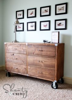 a wooden dresser sitting in front of a wall with pictures on the wall above it