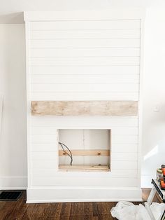 a room with white walls and wood flooring in the corner, including an unfinished fireplace