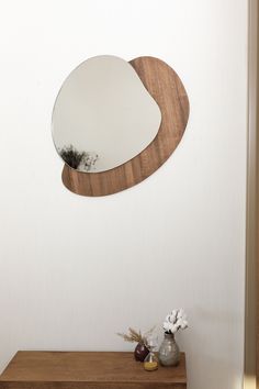 a mirror sitting on top of a wooden shelf next to a vase with flowers in it