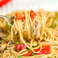 a fork full of noodles with meat and vegetables