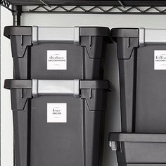 three gray bins with labels on them sitting next to each other in a room