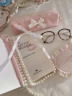 a pair of glasses sitting on top of a table next to a book and some pearls