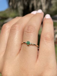 a woman's hand with a ring on it and a tree in the background