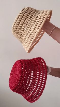 a hand holding a red and white crocheted hat