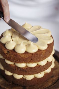 a person is cutting into a cake with white frosting on the top and bottom