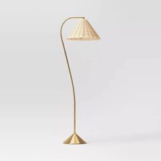 a gold floor lamp with a white shade on the base and a light bulb attached to it