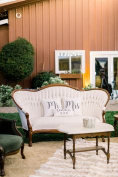 a white couch sitting on top of a rug in front of a wooden building with windows