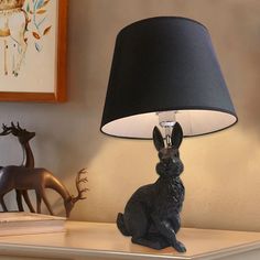 a black lamp sitting on top of a table next to a stuffed animal and deer figurine