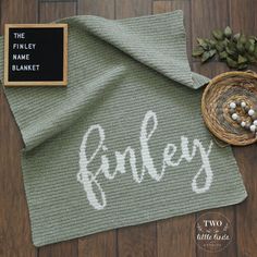 a knitted blanket with the word barley on it and a small bowl next to it