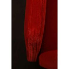 a red chair sitting in front of a black wall with the seat up and arm down