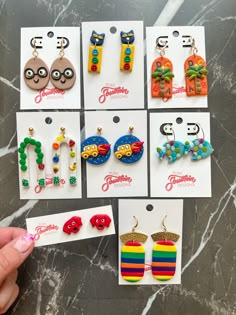 six pairs of colorful earrings are shown in front of each other on a marble surface