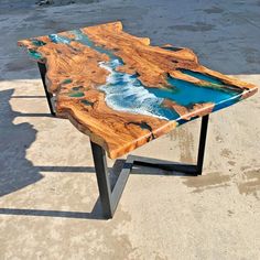 a table made out of wood and metal with blue water in the ocean on it