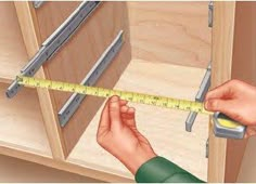 a person holding a measuring tape in front of a cabinet with drawers on both sides