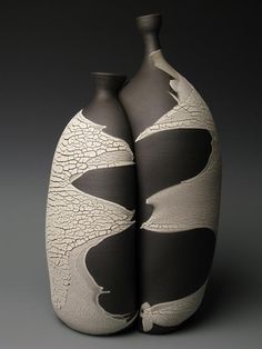 two black and white vases sitting next to each other on a gray table top