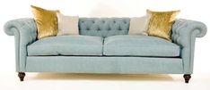 a light blue couch with gold pillows on the armrests and back rests against a white background