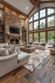 a large living room with wood floors and stone fireplace in the center, surrounded by windows