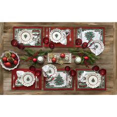 a christmas table setting with red and white plates, napkins, silverware and ornaments